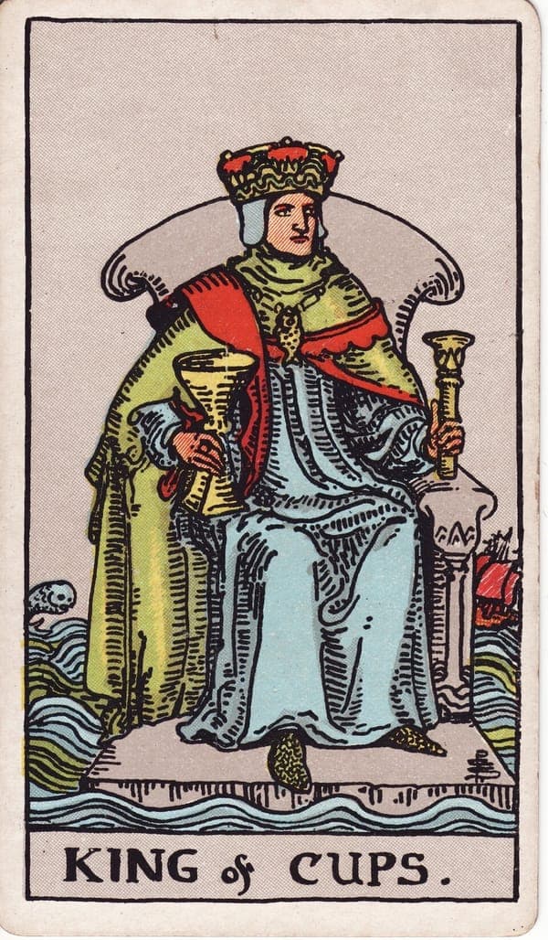 King of Cups tarot card: A king sits on a stone throne floating on a restless sea, holding a cup in one hand and a lotus sceptre in the other.