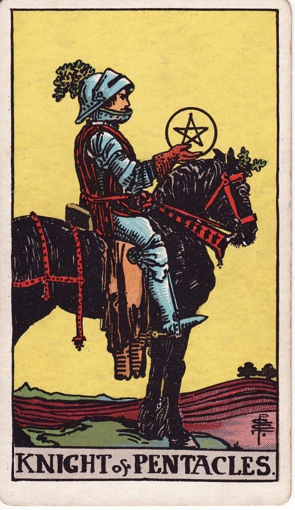 Knight of Pentacles tarot card: An armored knight sits motionless on a heavy black draught horse — bred for the plough, not the charge — in the middle of fields already tilled.