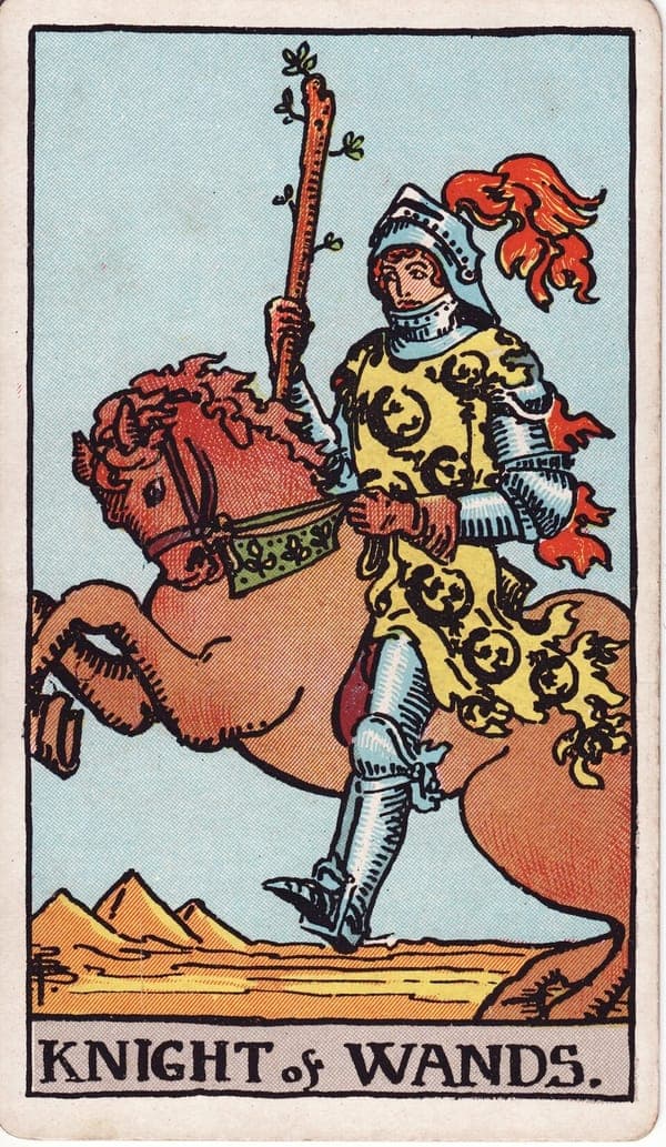Knight of Wands tarot card: An armored rider in a salamander-covered surcoat sits a rearing golden horse, wand couched like a lance, plume and mane streaming like flame.