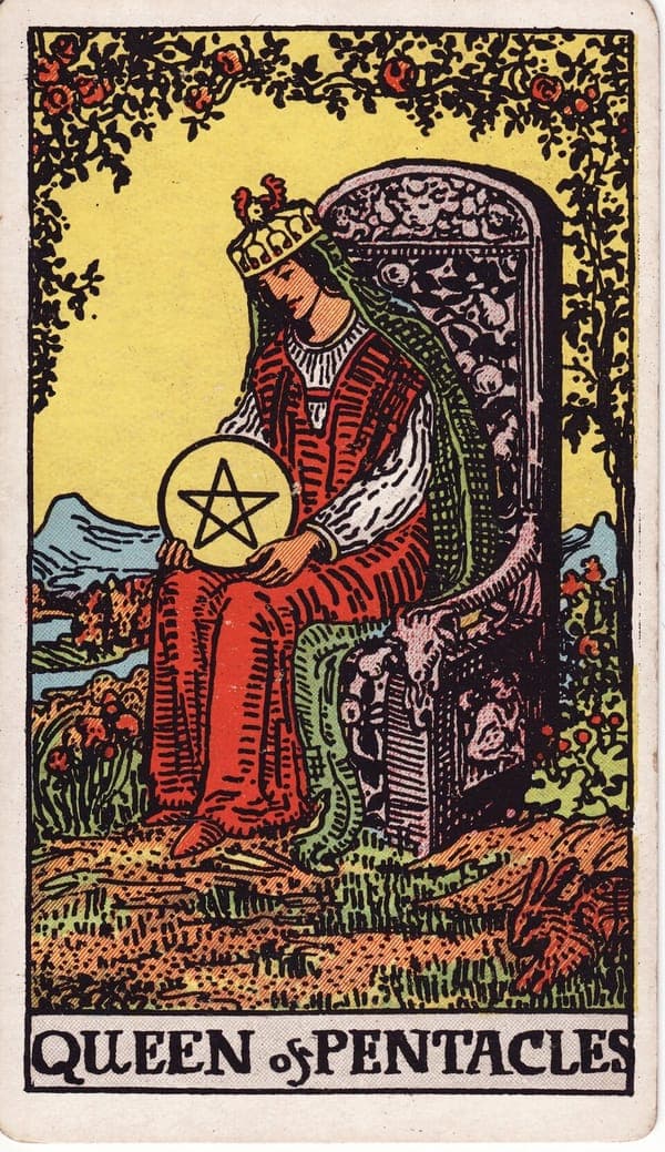 Queen of Pentacles tarot card: A queen sits on a throne carved with fruit, goats, and cherubs, in a garden arched with roses; she cradles a single pentacle in her lap with both hands, gazing down at it — wealth held like something alive.