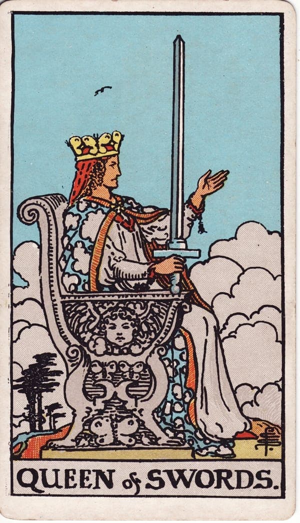 Queen of Swords tarot card: A queen sits in profile on a throne carved with a cherub and butterflies, her sword upright in one hand while the other extends open — demand and invitation at once.
