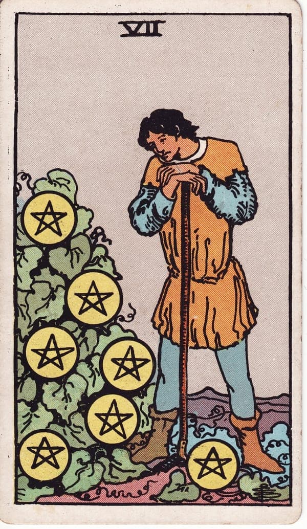Seven of Pentacles tarot card: A young farmer rests his chin on hands stacked atop a long hoe, gazing at a thick vine where seven pentacles hang like ripening fruit.