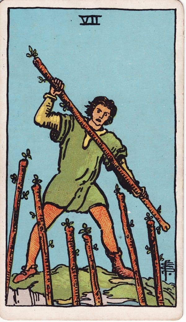 Seven of Wands tarot card: A man on raised ground swings his wand against six staves thrusting up from below — attackers unseen, only their challenge visible.