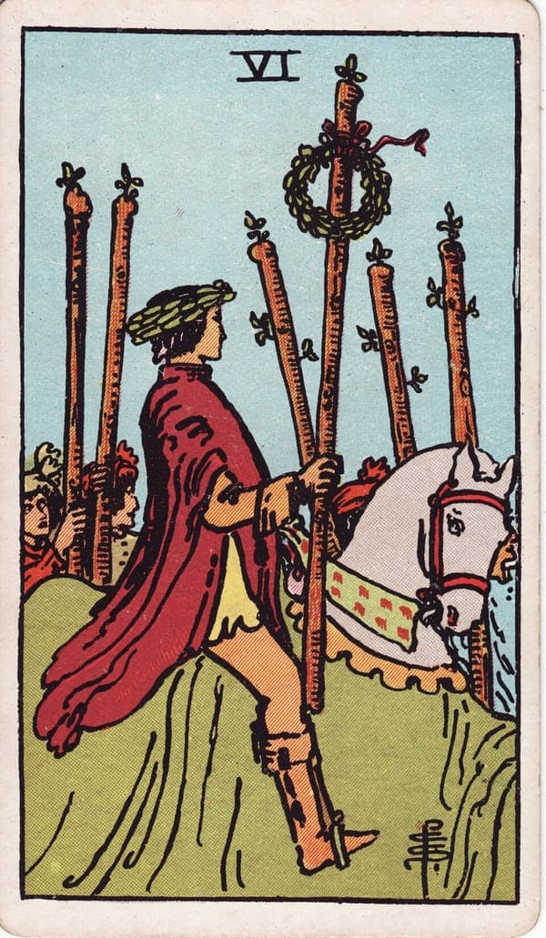 Six of Wands tarot card: A rider in a laurel wreath passes through a crowd on a white horse draped in green, a second wreath crowning the wand held high.