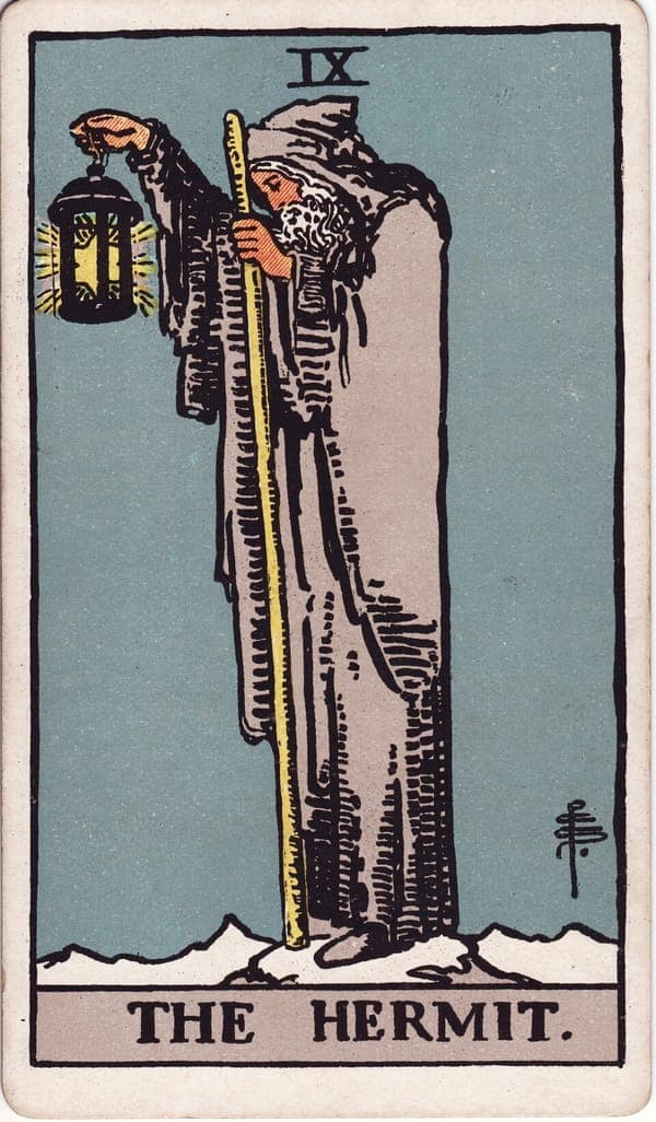 The Hermit tarot card — An old cloaked figure stands alone on a snowy peak, holding a lantern in which a six-pointed star sh