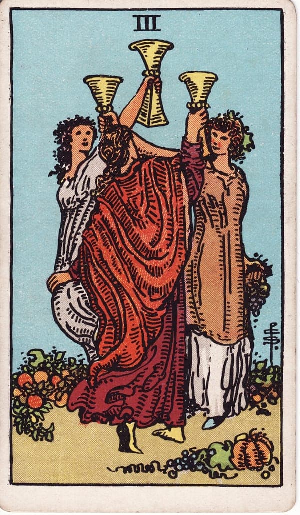 Three of Cups tarot card: Three women dance in a close circle, cups raised to meet at the center, garlands in their hair.