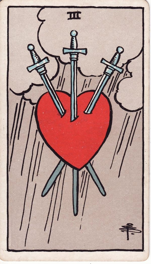 Three of Swords tarot card — A red heart floats against a grey sky, pierced symmetrically by three swords, rain falling in sheets