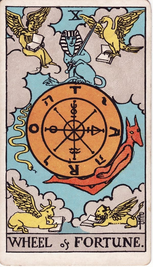 Wheel of Fortune tarot card — A great wheel inscribed with the letters T-A-R-O and alchemical symbols hangs in the sky, ringed by 