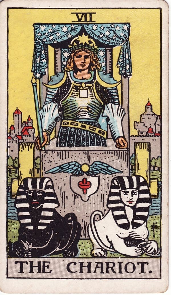 The Chariot tarot card: An armored figure stands in a chariot drawn by two sphinxes, one black and one white, pulling in subtly different directions.