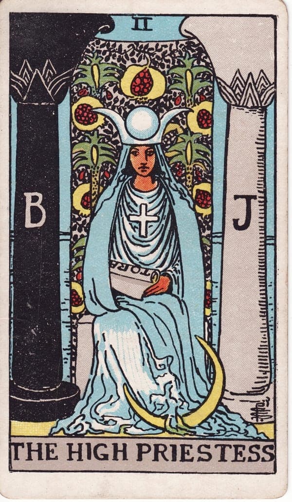 The High Priestess tarot card — A veiled figure sits between two pillars — one black (Boaz), one white (Jachin) — marking the thresh