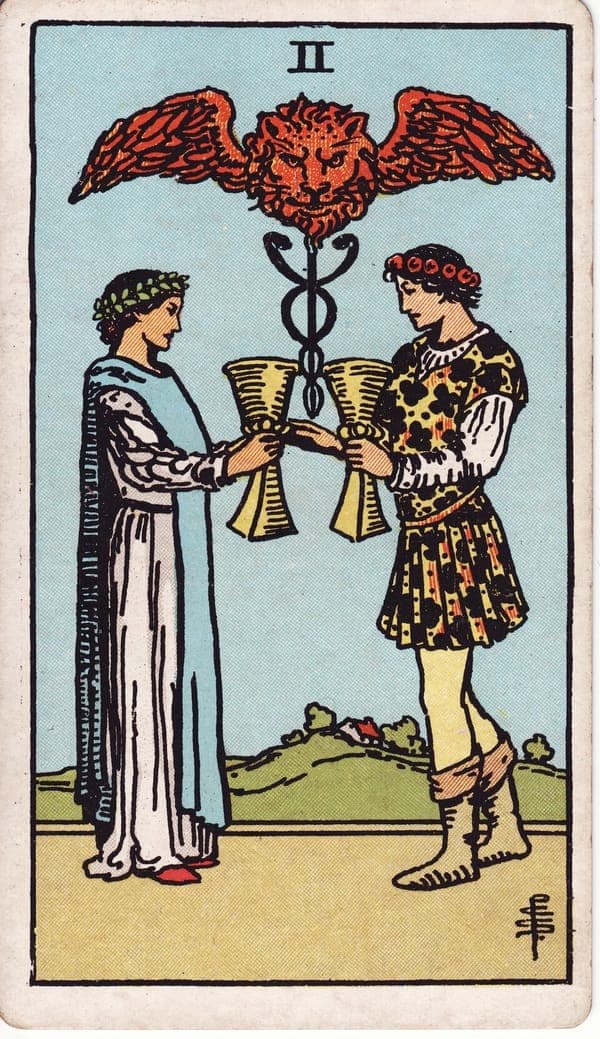 Two of Cups tarot card — Two figures face each other, each holding a cup, exchanging their vows across the space between them